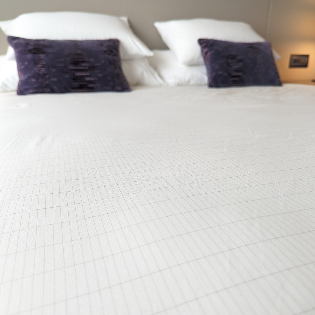 fitted grounding sheet on a king size bed with purple cushions