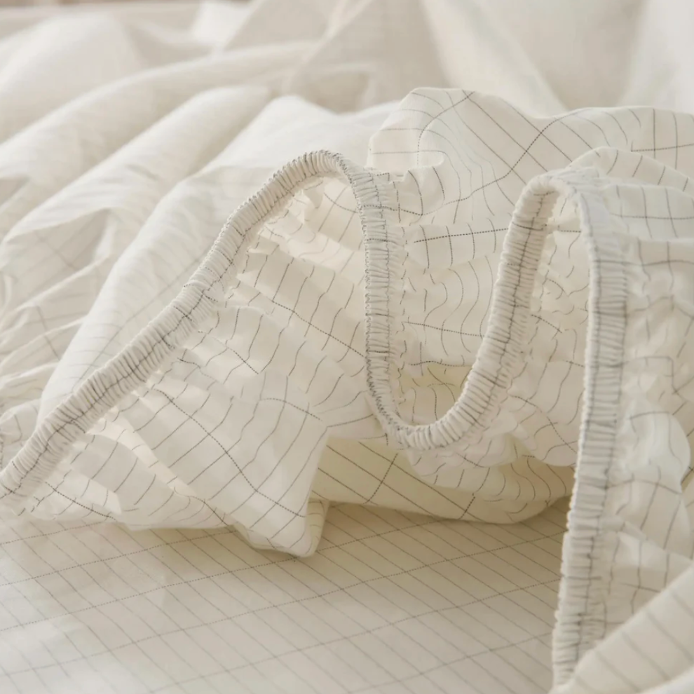 Image of a fitted grounding sheet laid on a king-sized bed, showcasing its ample coverage and subtle, natural color that blends with the room’s decor.